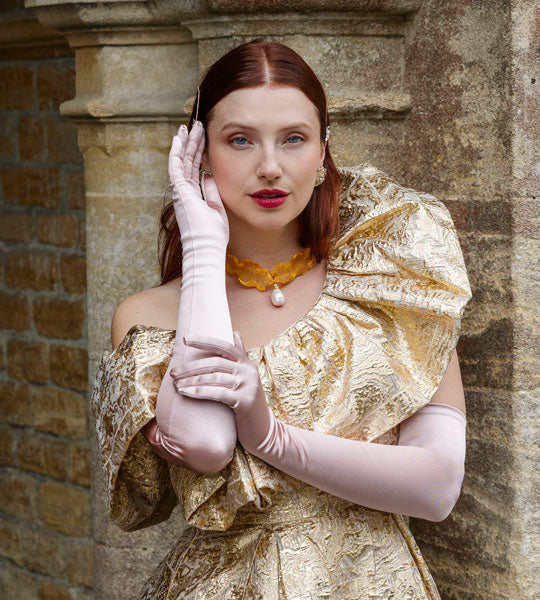 Woman wearing long satin gloves in rose with an evening dress outdoors