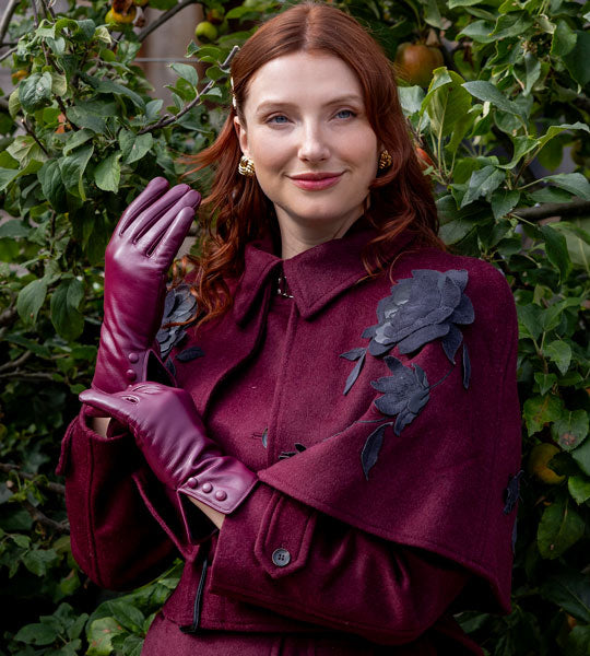 Woman wearing burgundy leather gloves with a matching colour coat outdoors