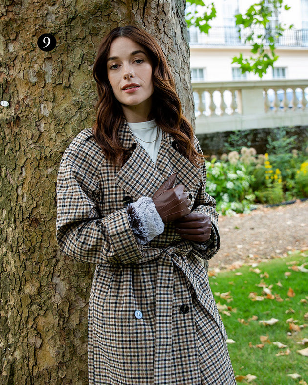 Woman wearing touchscreen three point lined leather gloves with faux fur cuffs in chestnut in the park